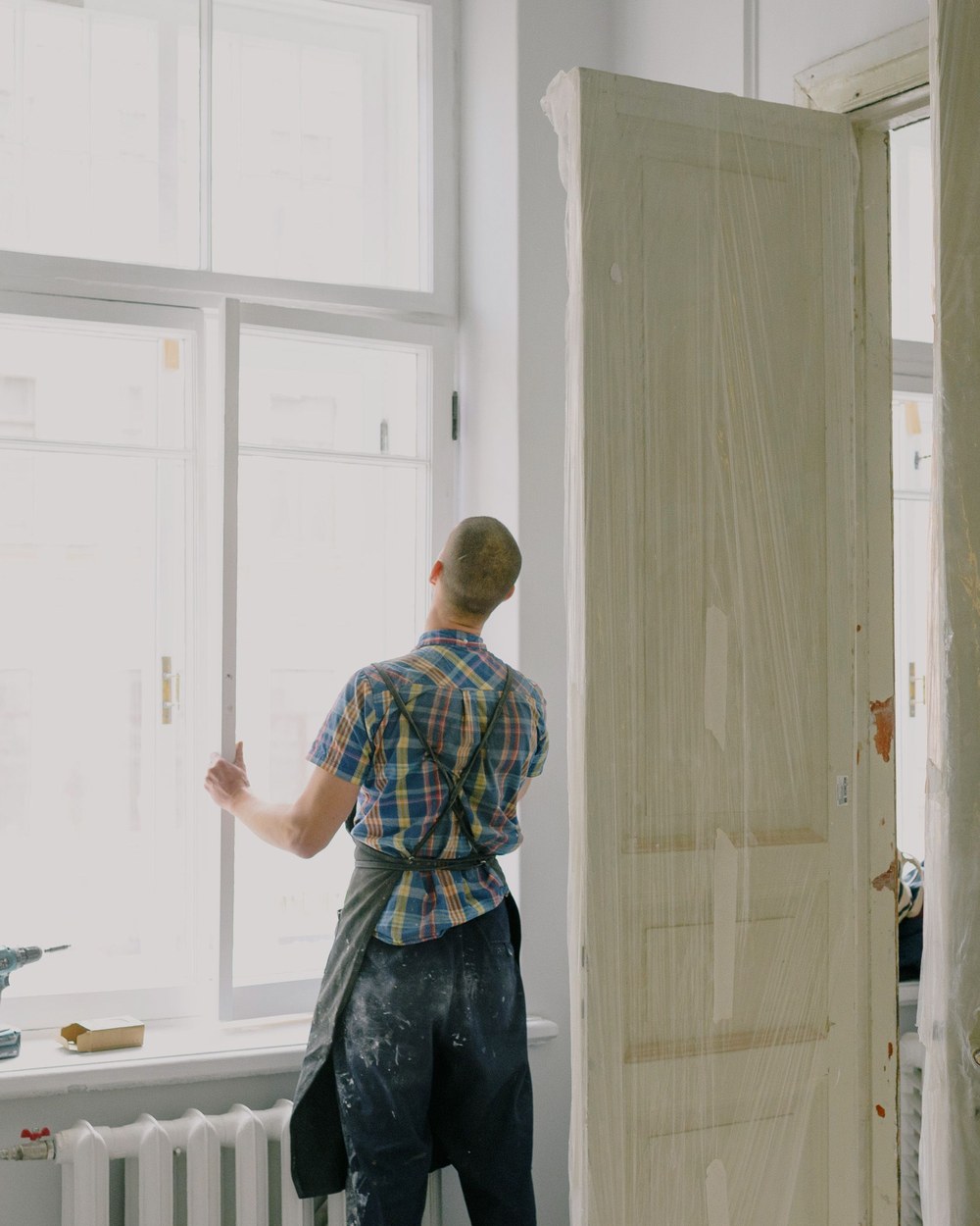 Working at a window with a replacement door nearby, illustrative stock photo