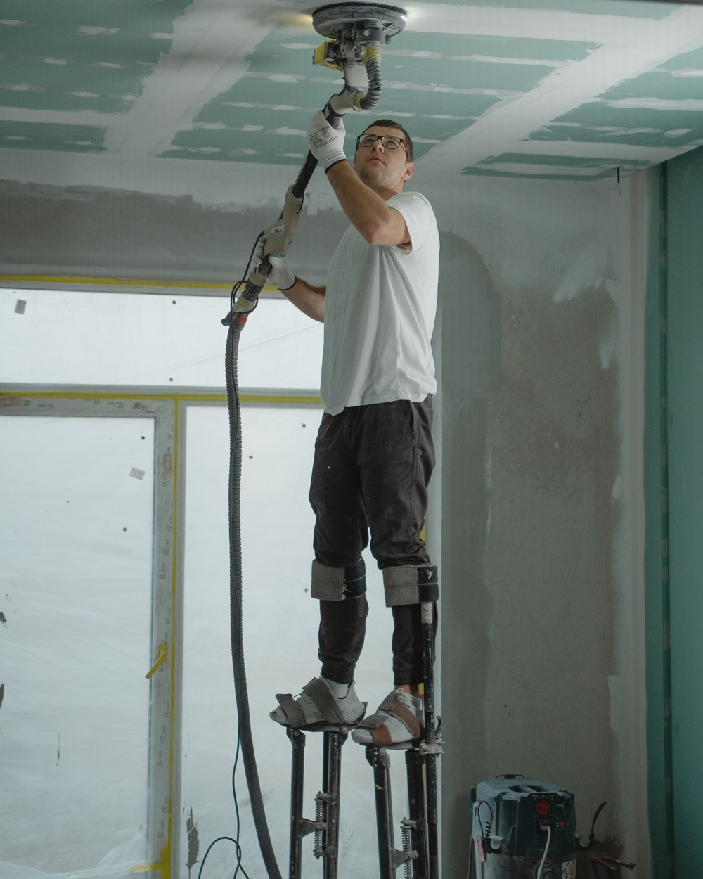 Drywall sanding in progress on stilts, illustrative stock photo